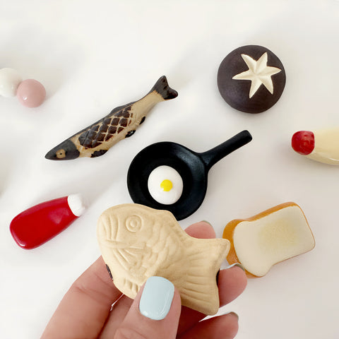 A variety of utensil rests, one being held by a female hand